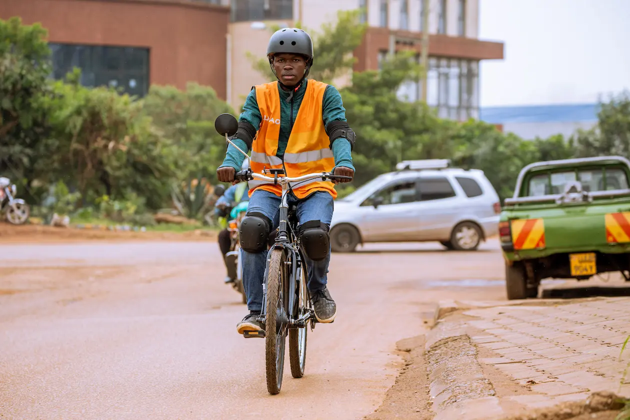 A rider in a hi-vis vest on a Karaa e-bike on a Kampala road