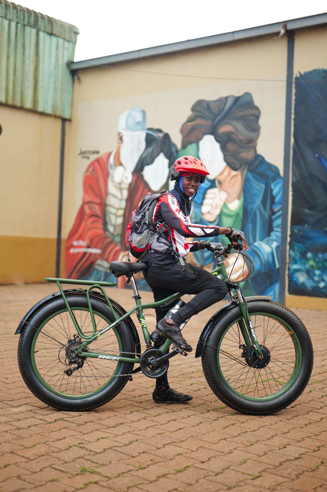 A rider on a green fat-tyre Karaa e-bike by a mural