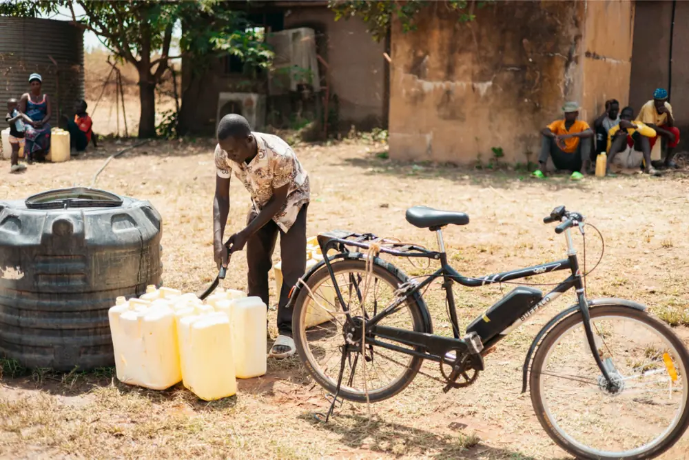 Loading jerrycans of water onto a Karaa e-bike at a water point
